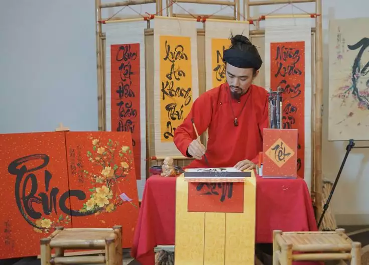 La tradition du Tết vietnamien illustrée par la calligraphie, un maître calligraphe traçant des caractères porte-sagesse lors du Nouvel An.